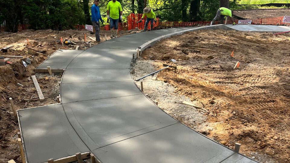 Concrete contractors levelling newly poured concrete sidewalk
