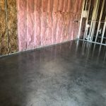 Our Work: A concrete floor in a room with pink insulation.