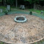 Our Work: A circular stone patio with a fire pit at its center.
