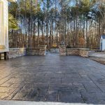 Our Work: A concrete patio with a fireplace in the background.