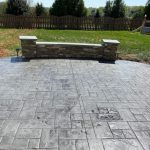 Our Work: A concrete patio with a bench and a fire pit.