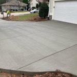 Our Work: A concrete driveway being poured in front of a house.