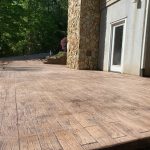 Our Work: A wood deck with stone pillars and trees in the background.