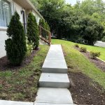 Our Work: Landscaping project featuring steps leading up to a house with beautiful grass and well-maintained shrubs.