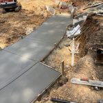 Our Work: A concrete walkway is being constructed on a construction site.