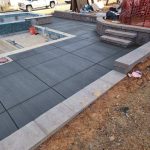Our Work: A concrete patio is being built next to a pool.