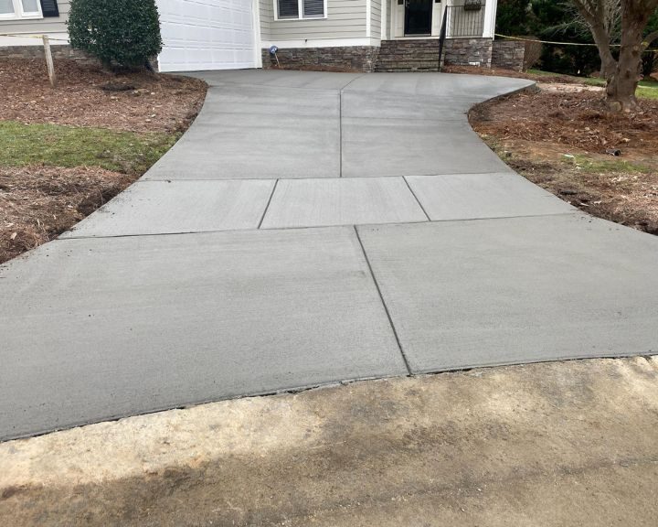 A concreted driveway in front of a house.