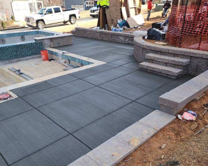 A concrete patio is being built in front of a house in the city.
